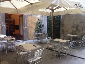 An outdoor café area with metal tables and chairs, covered by umbrellas with the brand name 'ZONIN'. - Albergo Filippeschi (Orvieto)