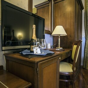 A wooden desk with a television, a bottle of champagne, two wine glasses, and a lamp. - Albergo Filippeschi (Orvieto)