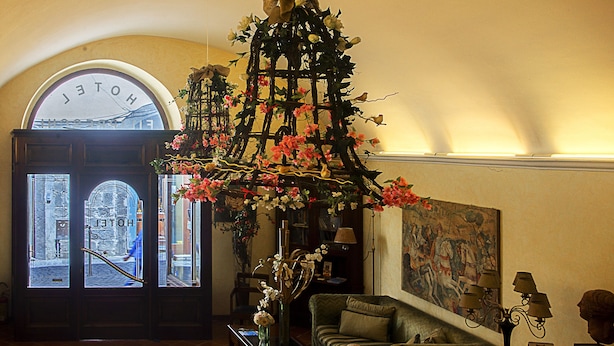 Un hall d’hôtel avec une grande porte en arc de cercle, un arrangement floral, un tableau et un canapé.