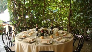 A round table set for a meal with plates, glasses, and a bottle of wine, surrounded by chairs. - Hotel Paradiso (Spoleto)