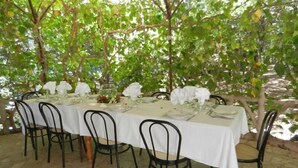A table set for six with white tablecloths, black chairs, and a natural backdrop of trees and foliage. - Hotel Paradiso (Spoleto)