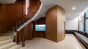 Un interior moderno con una escalera curva, un televisor de pantalla plana y una zona de estar con vistas.