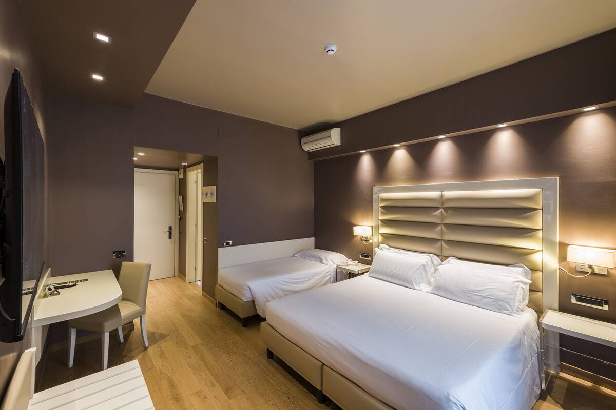 A hotel room with two beds, a desk, and a chair.