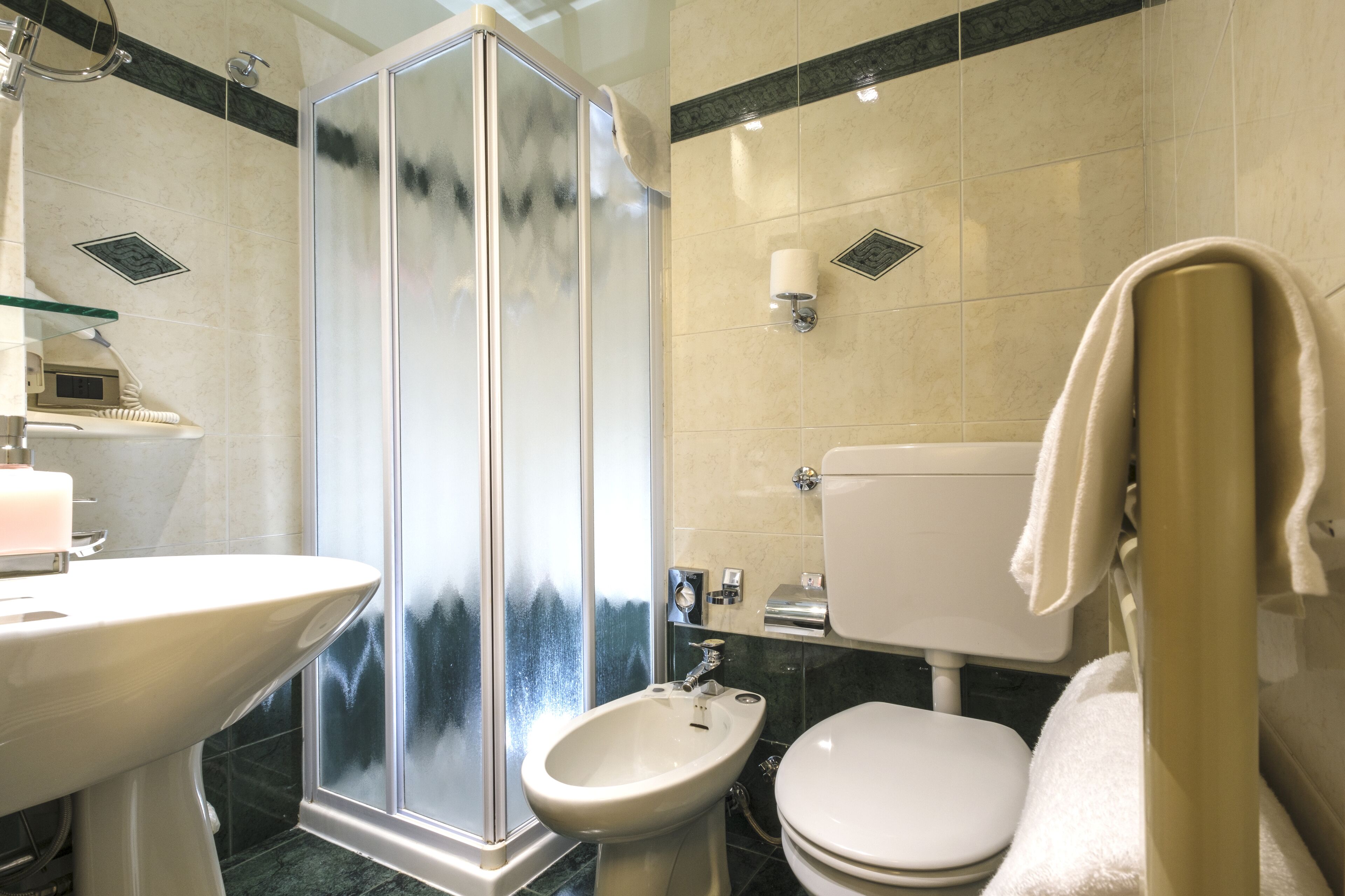 Et badeværelse med et glasafskærmet brusebad, et væghængt håndvask, et karbad og et toilet.