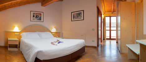 Un dormitorio con una cama de madera, dos mesitas de noche con lámparas, suelo de madera y techo de madera.