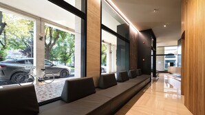 Un área de recepción moderna con un banco largo, una bicicleta y vista a los coches estacionados afuera.