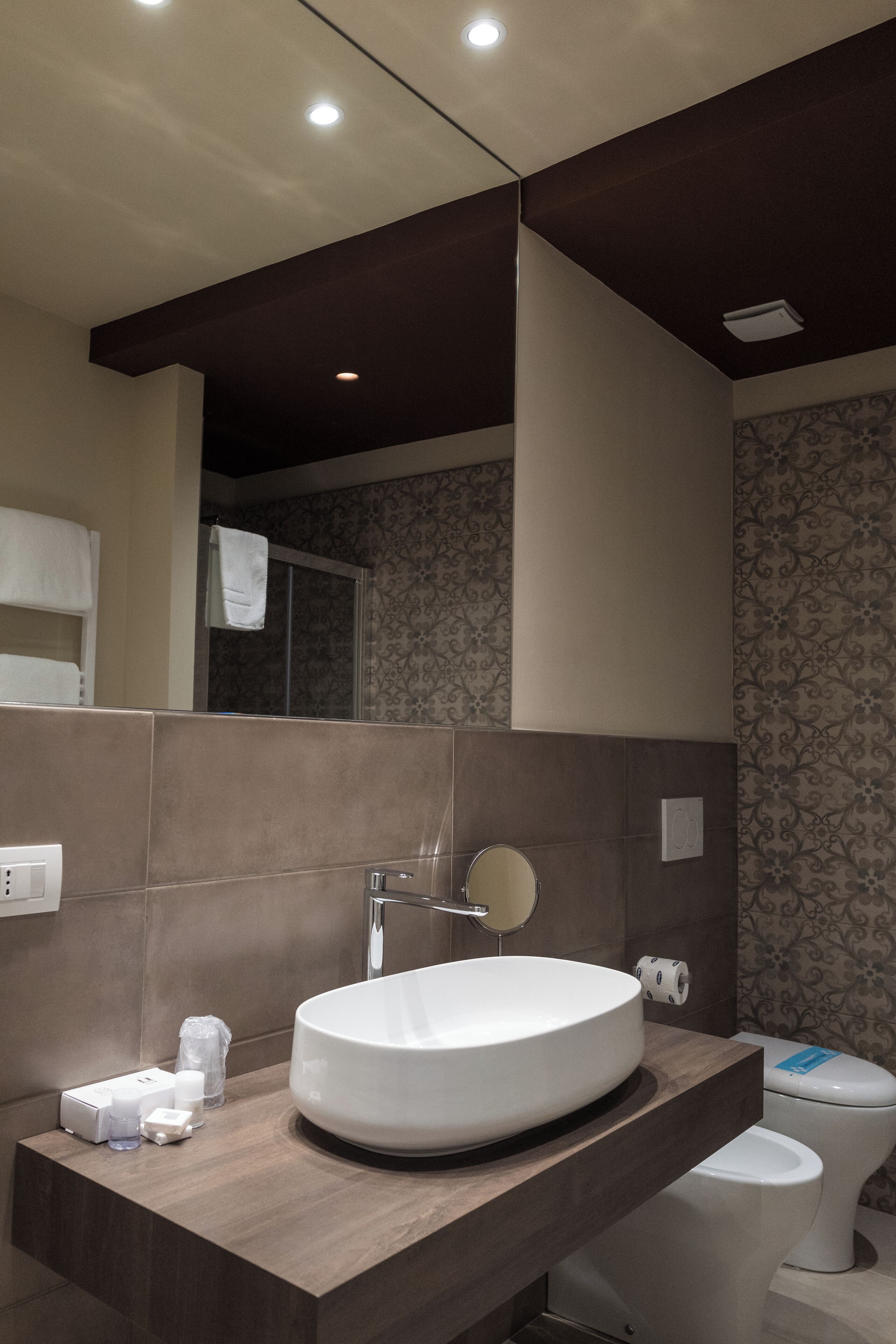 A modern bathroom with a large round sink, a mirror, and a toilet.