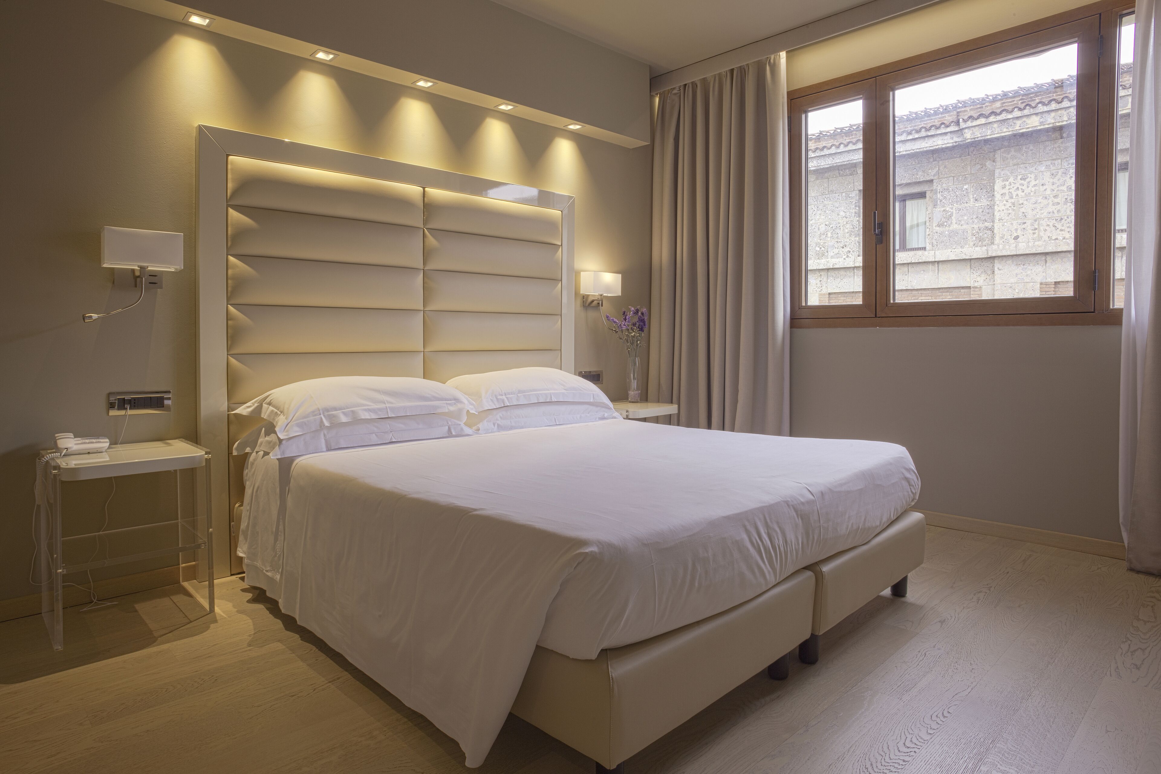 A modern bedroom with a large bed, bedside tables, and a window with curtains.