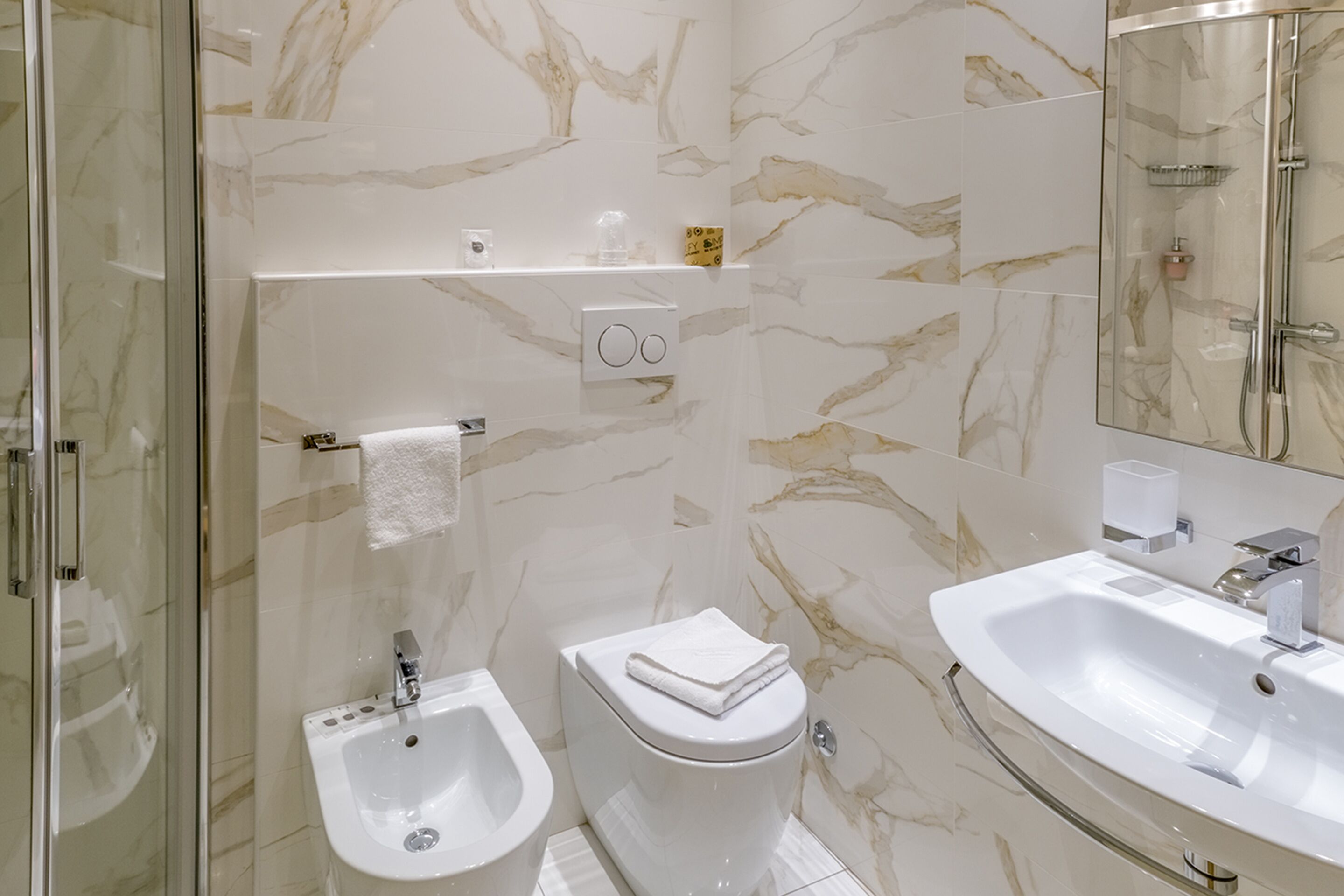 Une salle de bain avec un bidet, des toilettes et un lavabo, le tout de couleur blanche.