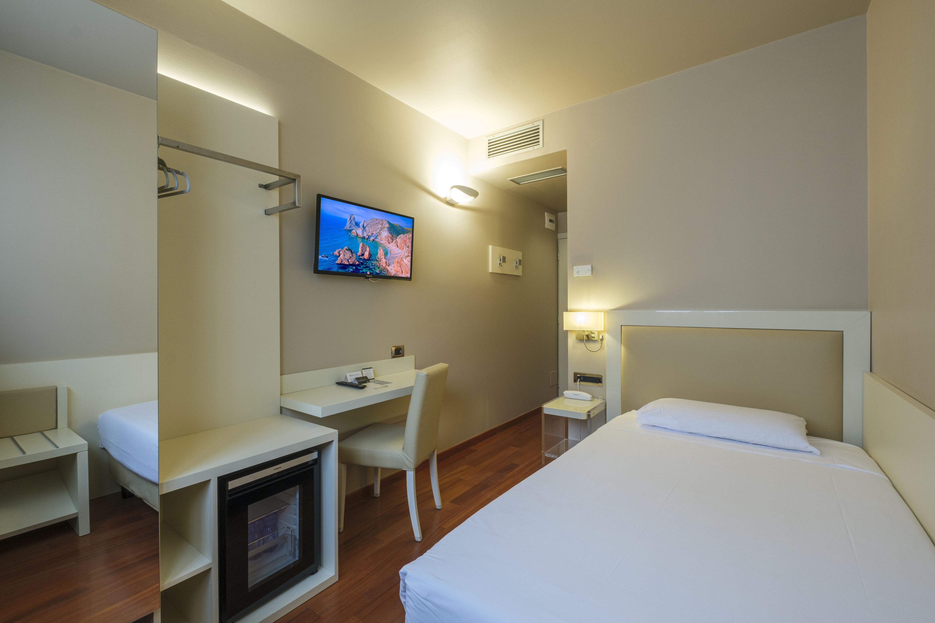 A hotel room with a bed, a desk, a chair, a television, and a bathroom.