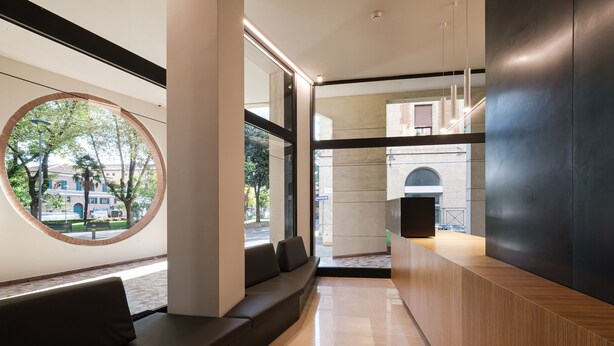 Una moderna zona de recepción con área de descanso, ventanas amplias y vista a la calle.