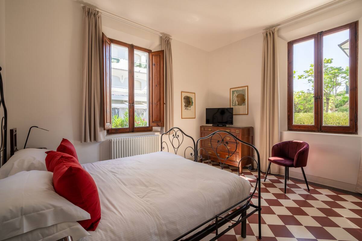 Un dormitorio con cama, cómoda, silla y televisor.