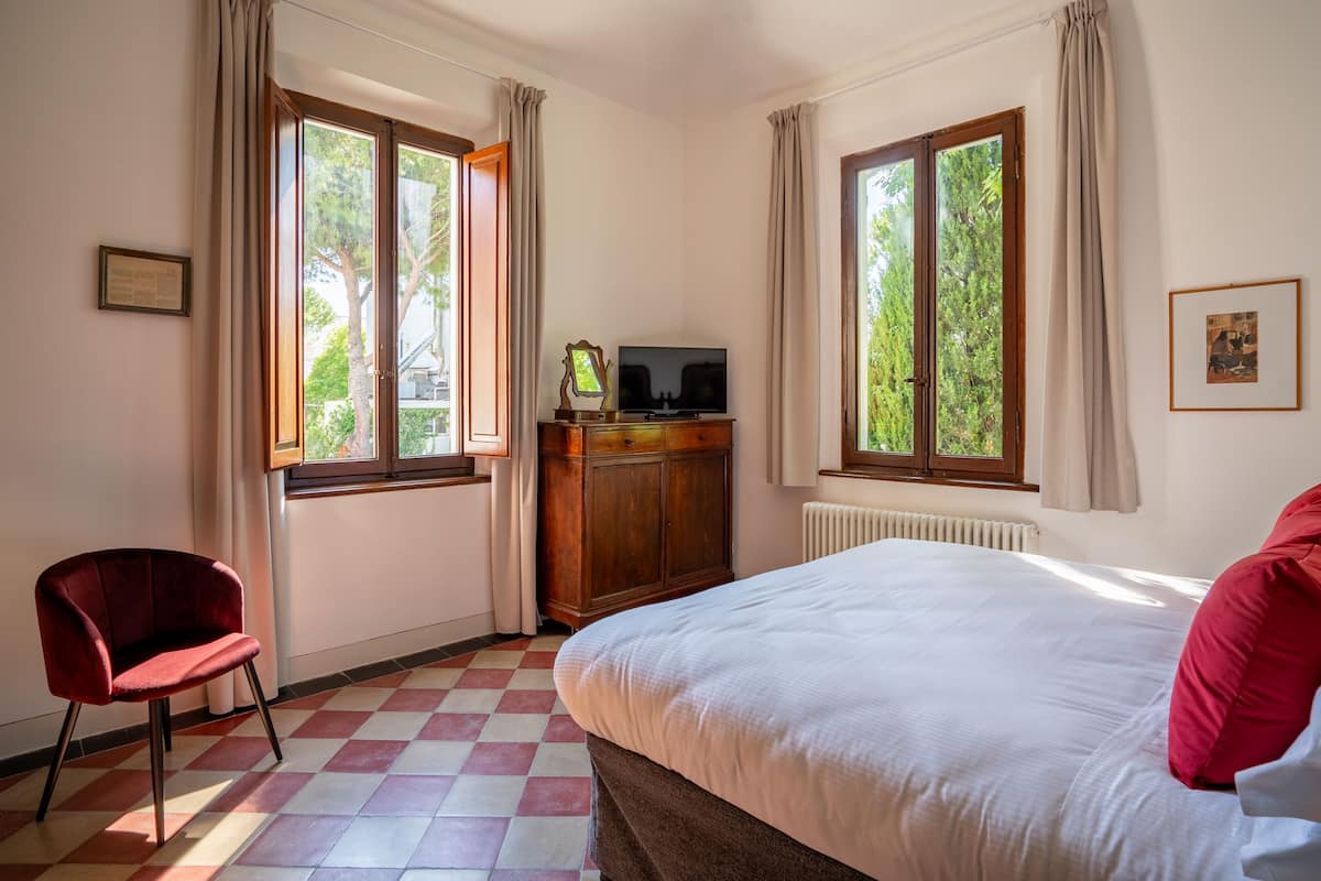 Una habitación de hotel con una cama, un armario de madera, un televisor y una silla.