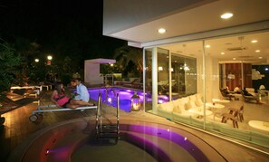 A modern outdoor pool area with a glass enclosure, lounge chairs, and a small waterfall feature. - Hotel Select Suites & Spa / Apartments (Riccione)