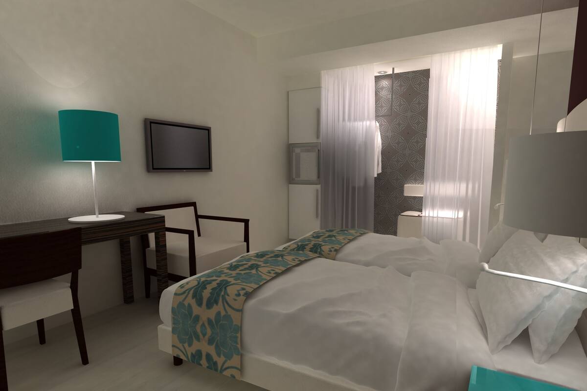 Une chambre d’hôtel comprenant un lit, un bureau, une chaise, une télévision et une salle de bain avec douche et toilettes.