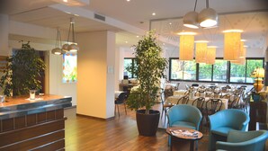 A modern interior with a reception desk, seating area, and dining space. - Hotel Sagittario (Padova)