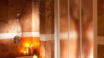 Une salle de bain avec une douche, une baignoire et une fenêtre en verre dépoli.