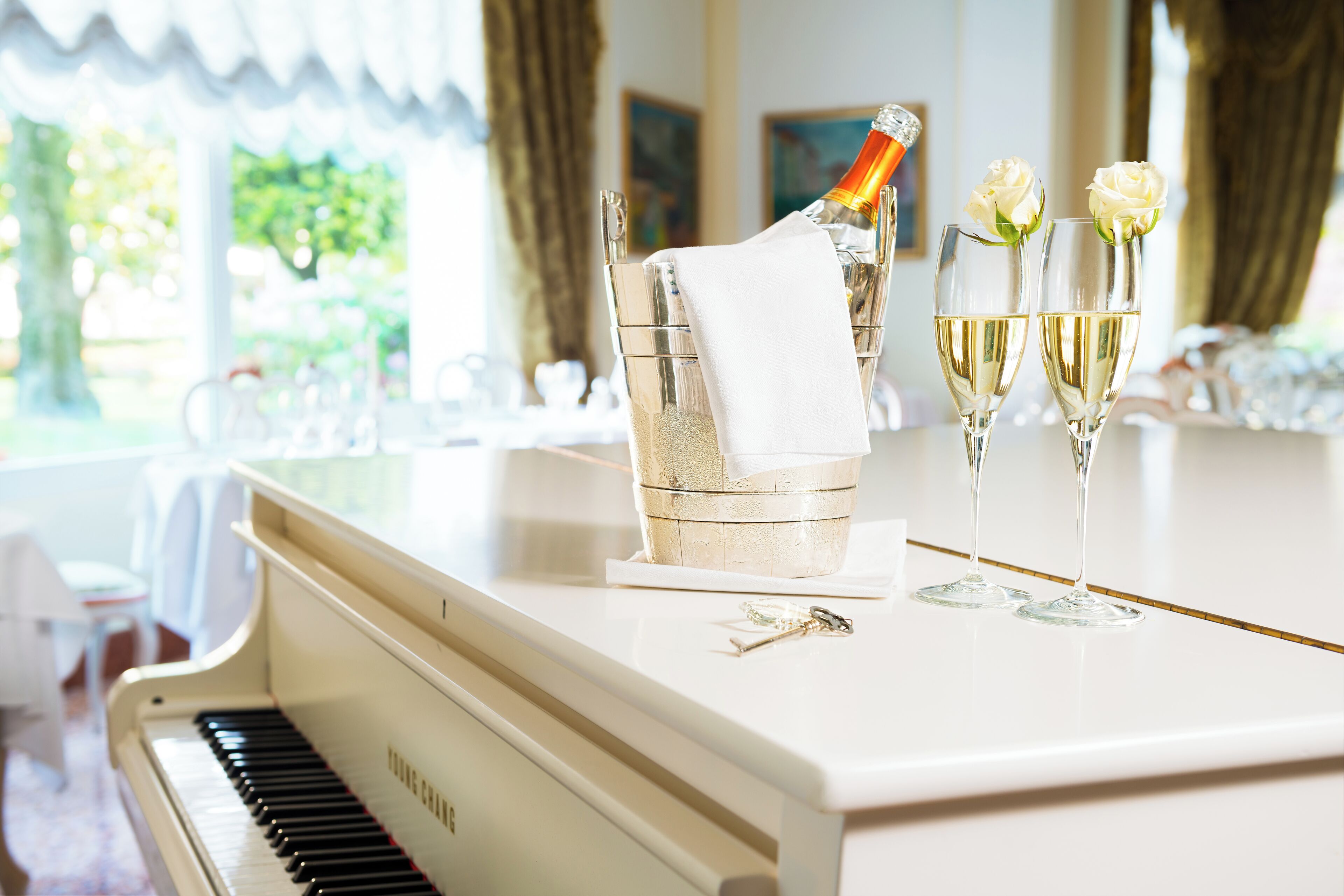 Ein Klavier, eine Champagnerflasche und zwei Gläser mit Rosen auf einem Tisch.