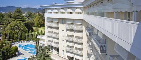 A hotel with multiple balconies, a swimming pool, and a view of the surrounding landscape.