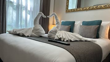 A hotel room with a neatly made bed, a remote control, and a mirror with a decorative frame.