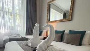 A hotel room with a large bed, a mirror, and two swan-shaped towels. - Tudor Court Hotel (London)