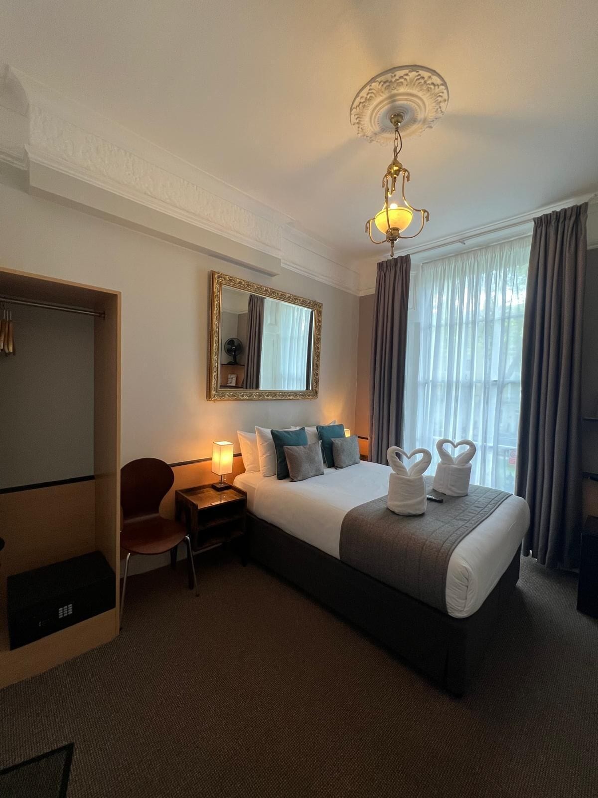 Ein Hotelzimmer mit einem großen Bett, einem Schreibtisch, einem Stuhl, einem Kleiderschrank und einem Spiegel.