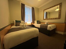 Habitación de hotel con dos camas, un espejo grande y una ventana con cortinas.