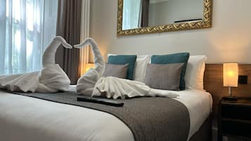 Ein Hotelzimmer mit einem ordentlich bezogenen Bett, einer Fernbedienung und einem Spiegel an der Wand.