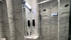 A modern bathroom with a glass-enclosed shower, a white sink, and a toilet. - Tudor Court Hotel (London)