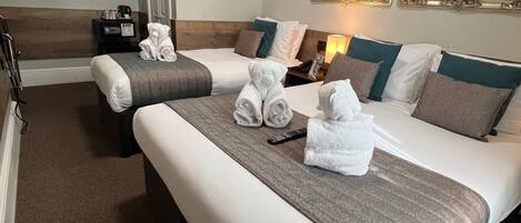 A hotel room with two beds, a bedside table, a mirror, and an air conditioning unit.