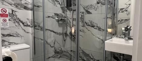 Un bagno moderno con doccia vetro, water e lavabo con specchio.
