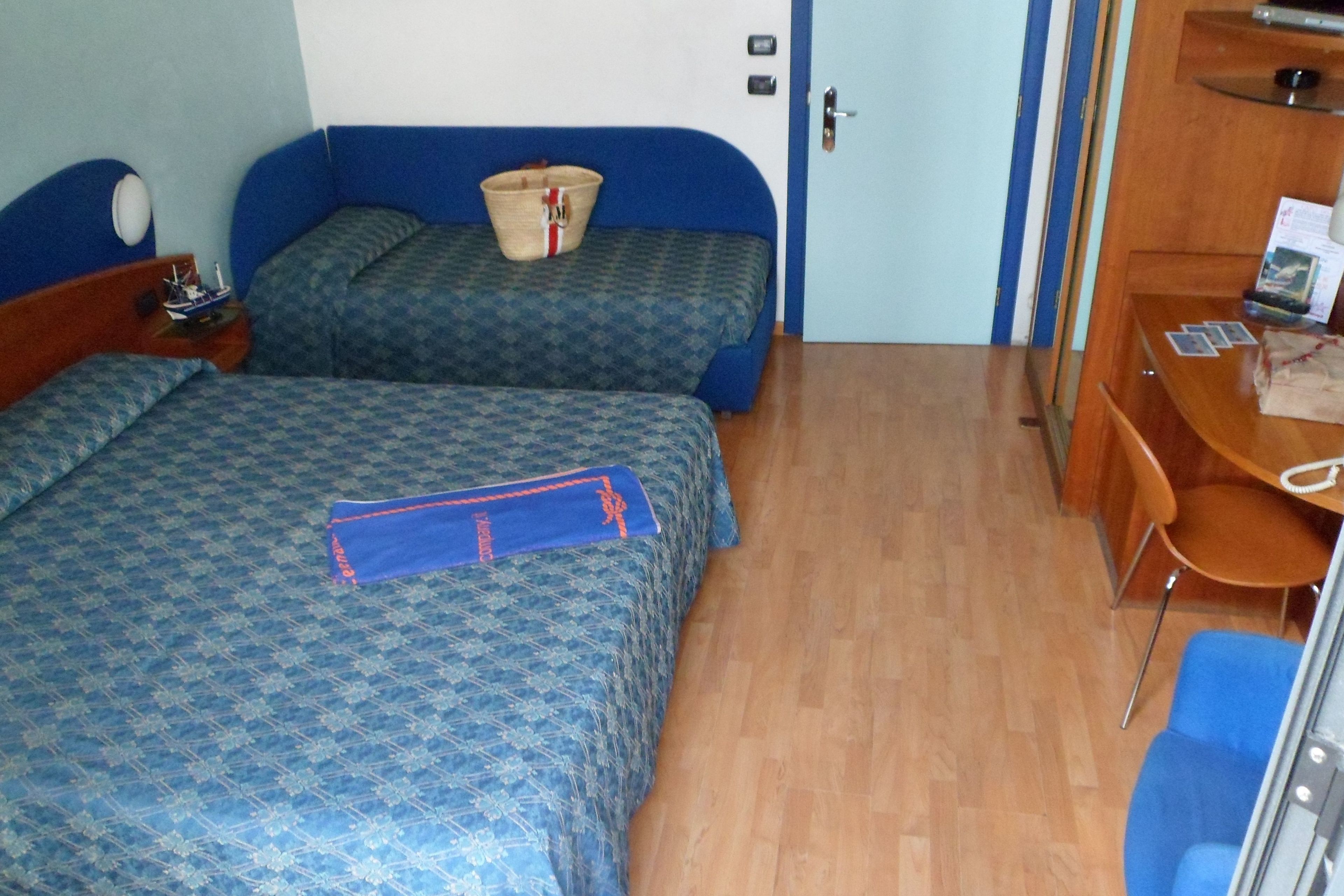 A hotel room with two beds, a desk, and a chair.