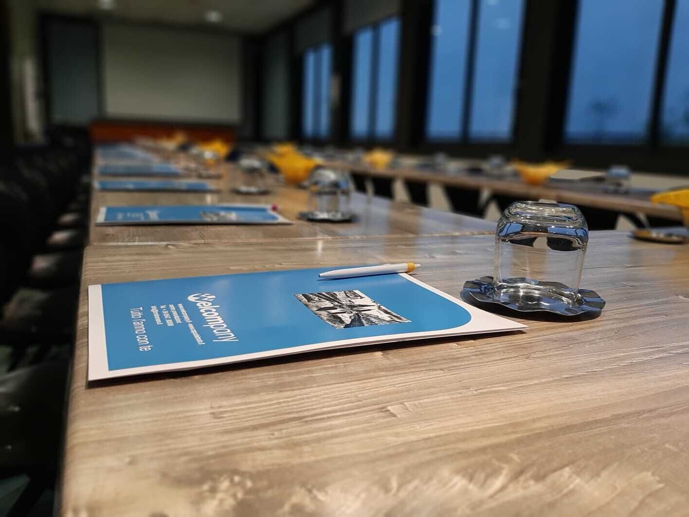 A conference room with a long table, blue name cards, and glasses of water.