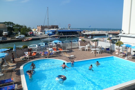 Una piscina al aire libre, sombrillas, sillones reclinables de piscina
