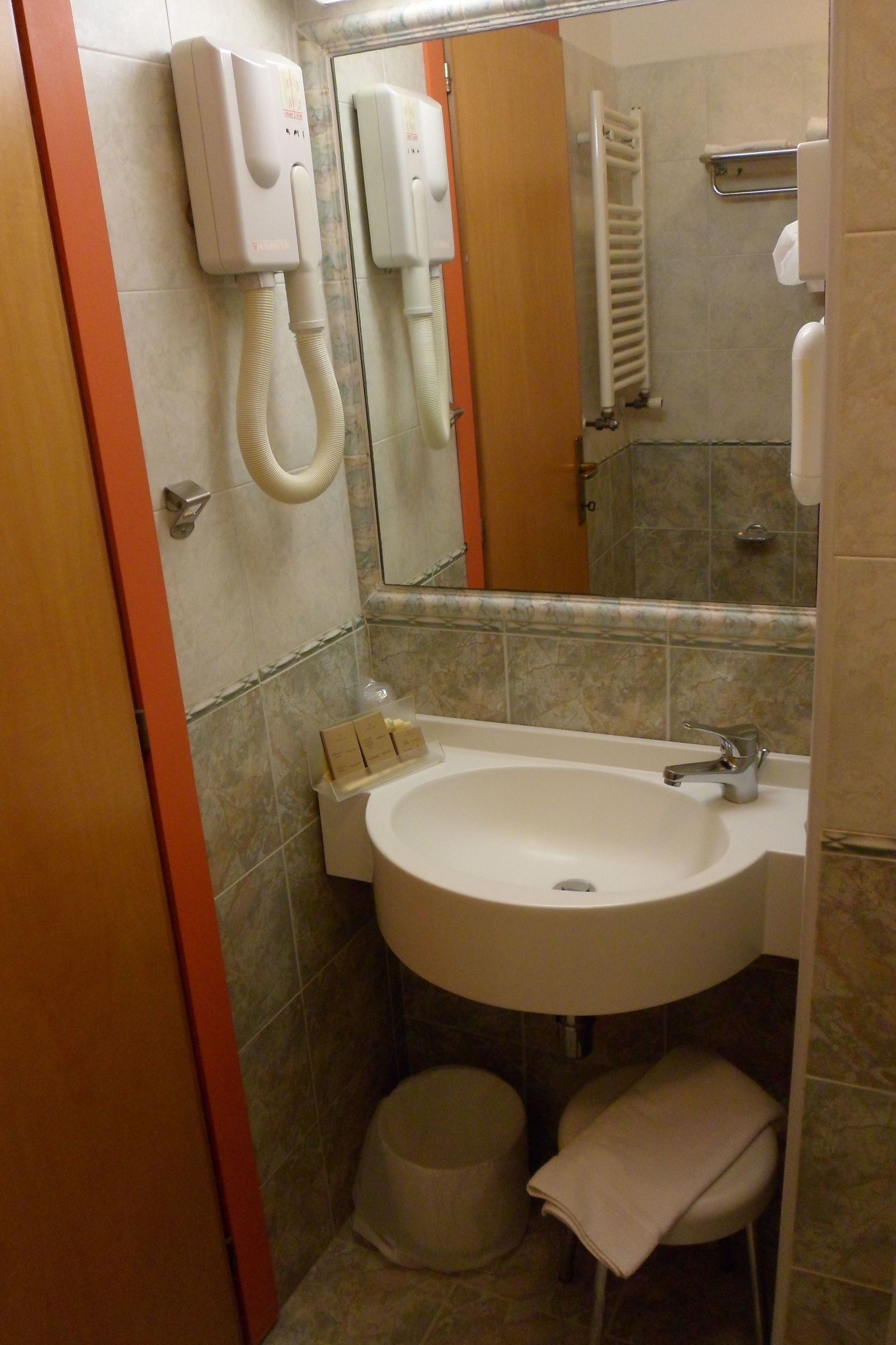 Un baño con lavamanos, espejo, toallero y secador de pelo.