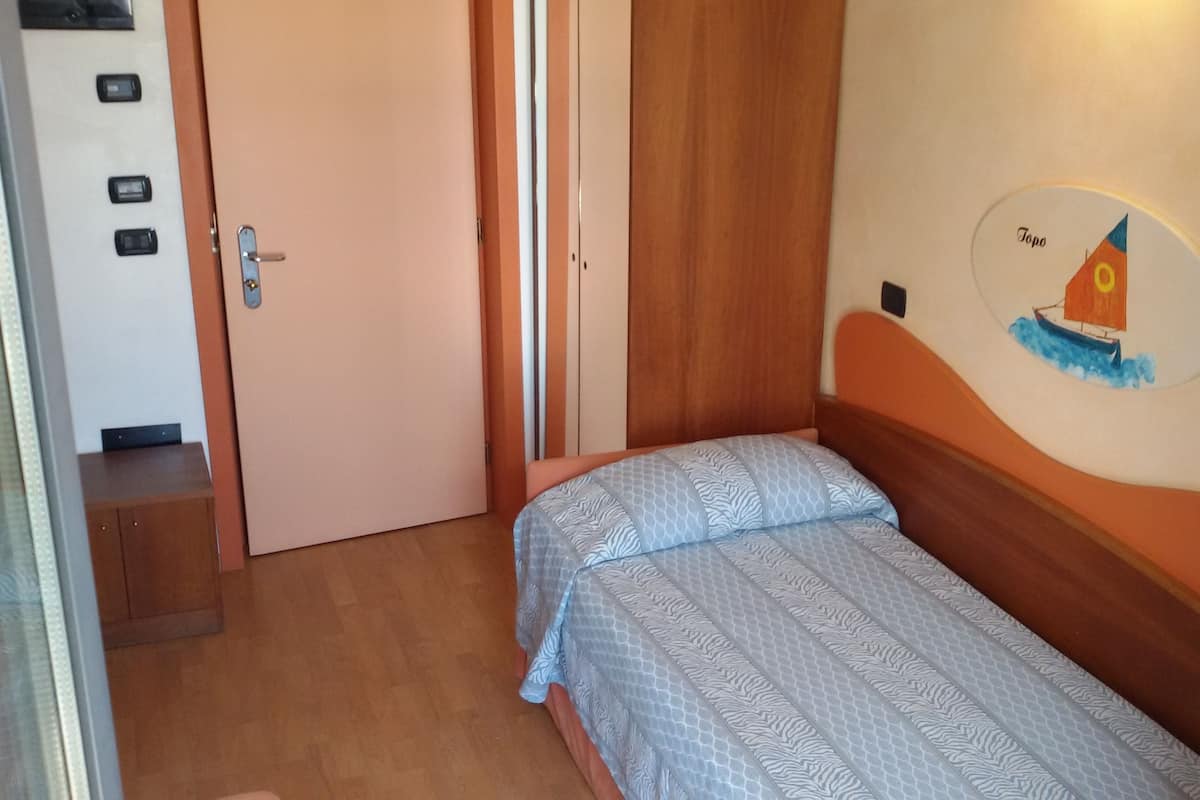 A bedroom with a bed, a wooden wardrobe, a door, and a wall decoration.