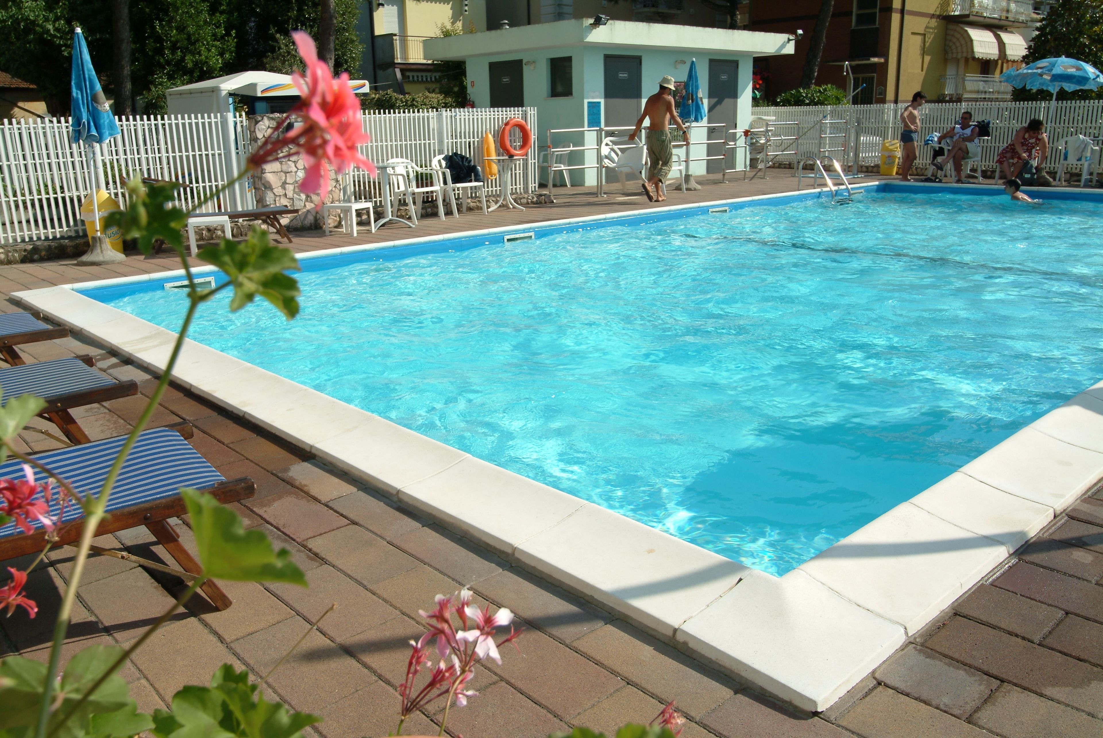 A swimming pool with a white deck, lounge chairs, and a lifeguard stand.