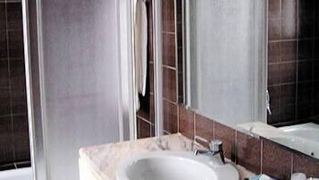 Ein Badezimmer mit Waschbecken, Spiegel und Duschkabine.