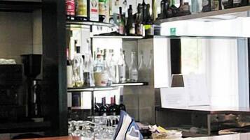 A bar area with shelves of bottles and glasses, a counter with a shoe, and a menu board.
