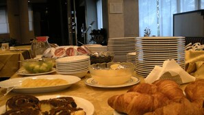 Ein Buffet mit verschiedenen Speisen, darunter Croissants, Kuchen und eine Fruchtschale.