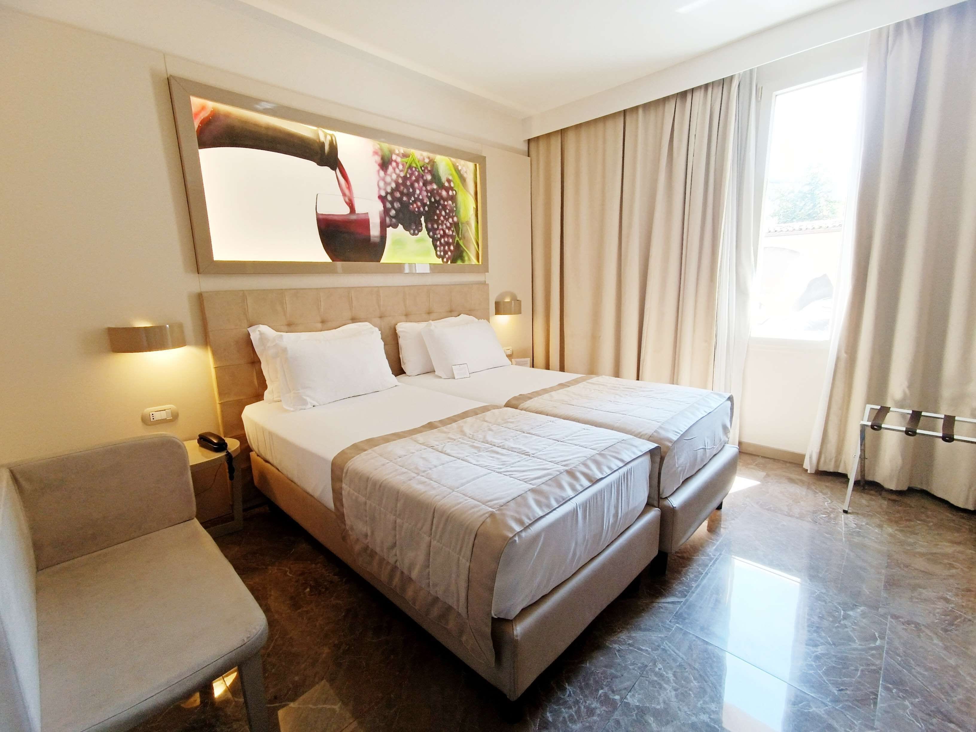 Een hotelkamer met een groot bed, een stoel, een bureau en een raam met gordijnen.