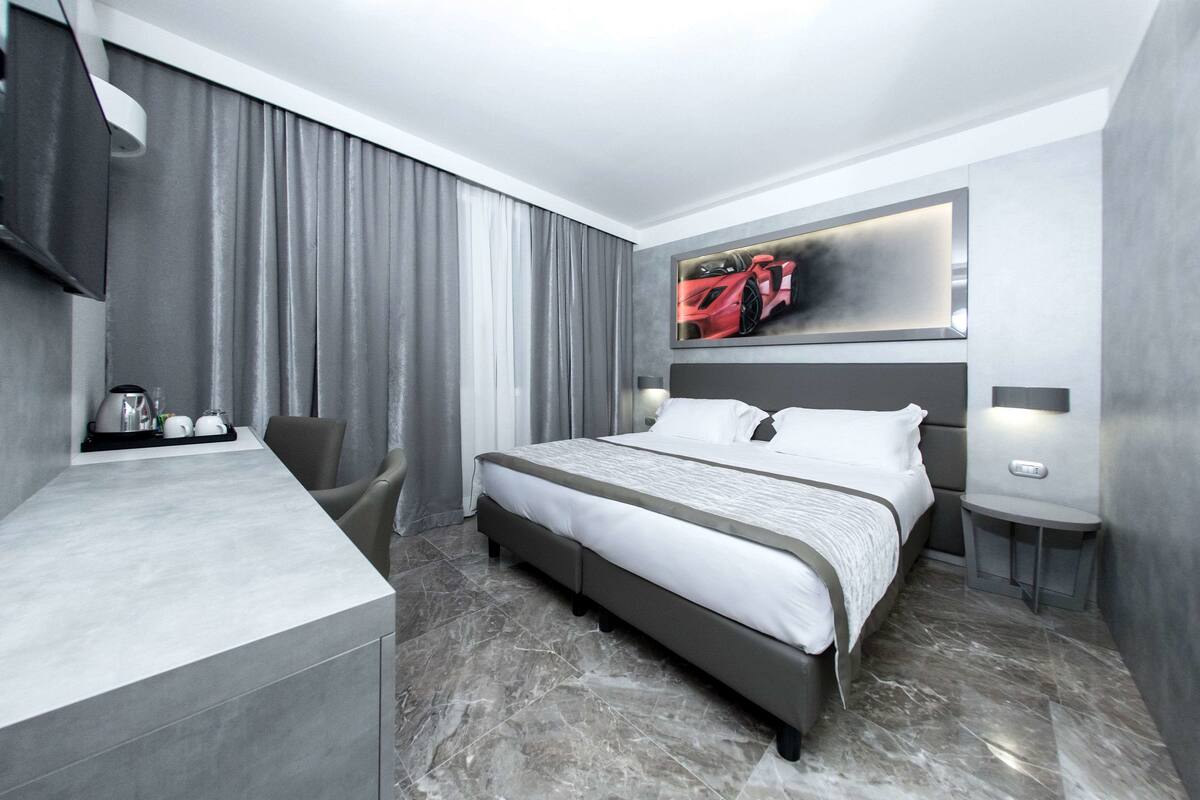 A modern hotel room with a large bed, a desk, and a chair.