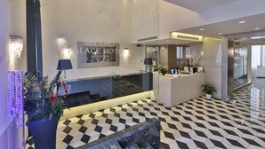 A hotel reception area with a modern design, featuring a check-in counter, a reception desk, and a decorative plant. - Best Western Premier Milano Palace Hotel (Modena)