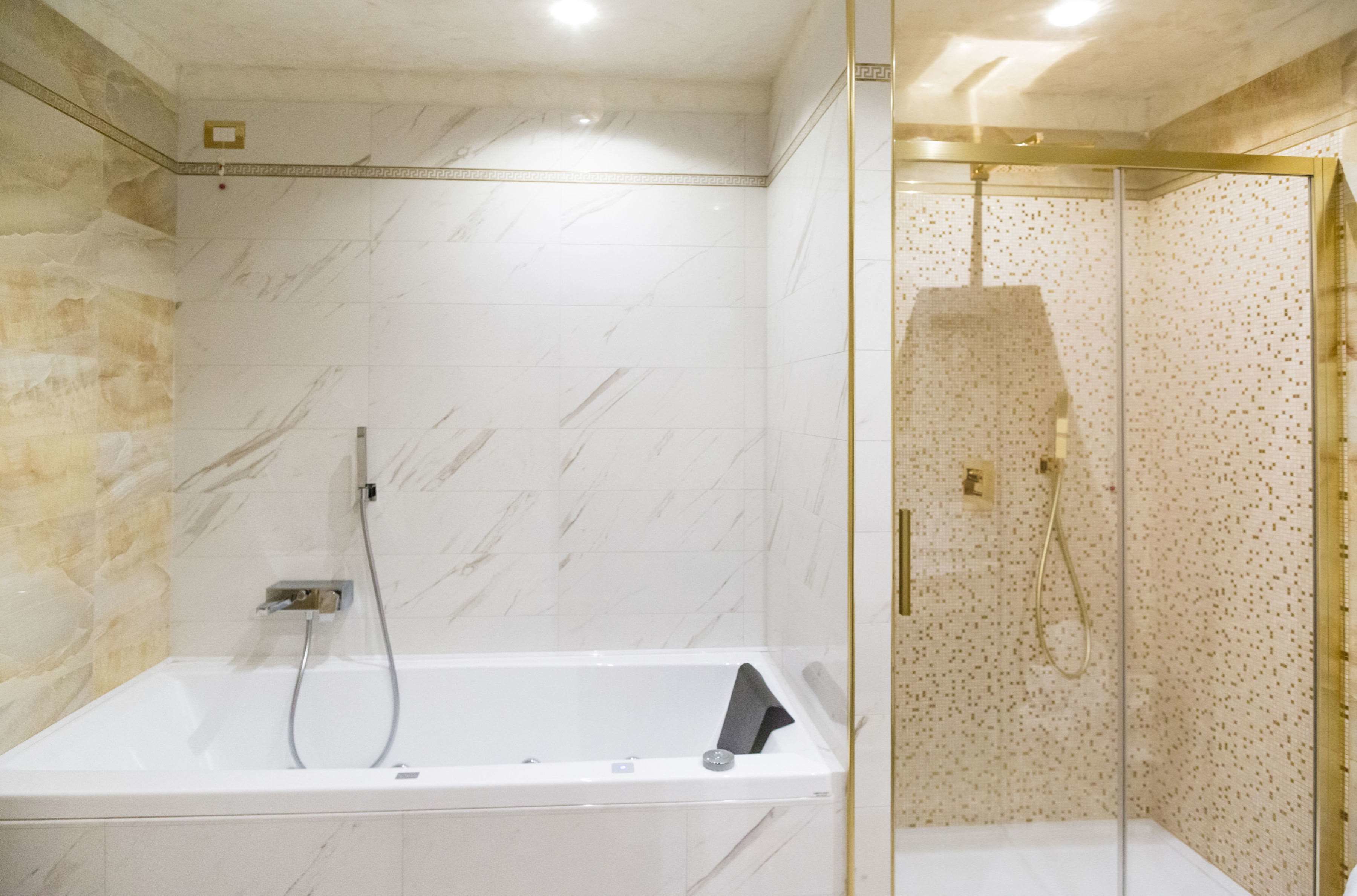 A modern bathroom with a bathtub, a shower area, and marble walls.