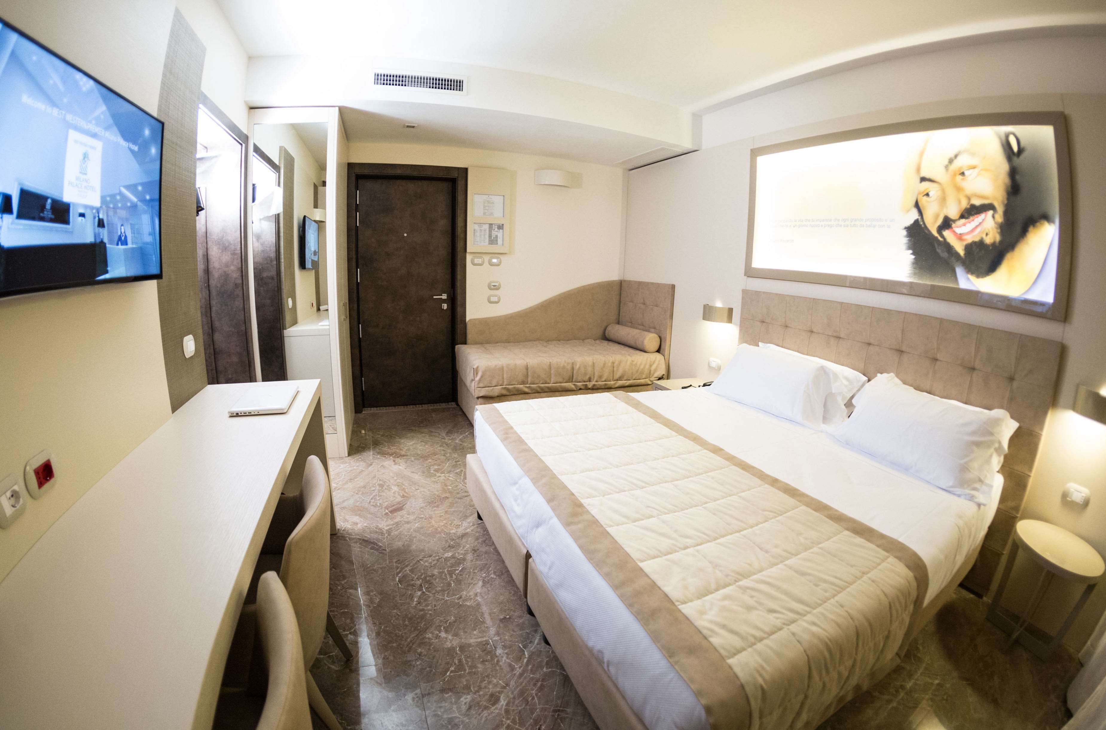 A hotel room with a bed, a desk, and a TV.