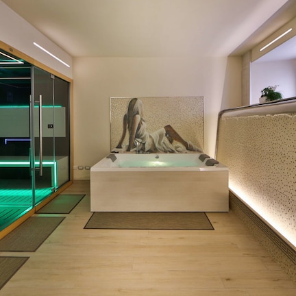 A modern bathroom with a glass-enclosed shower, a large bathtub, and a mosaic wall.