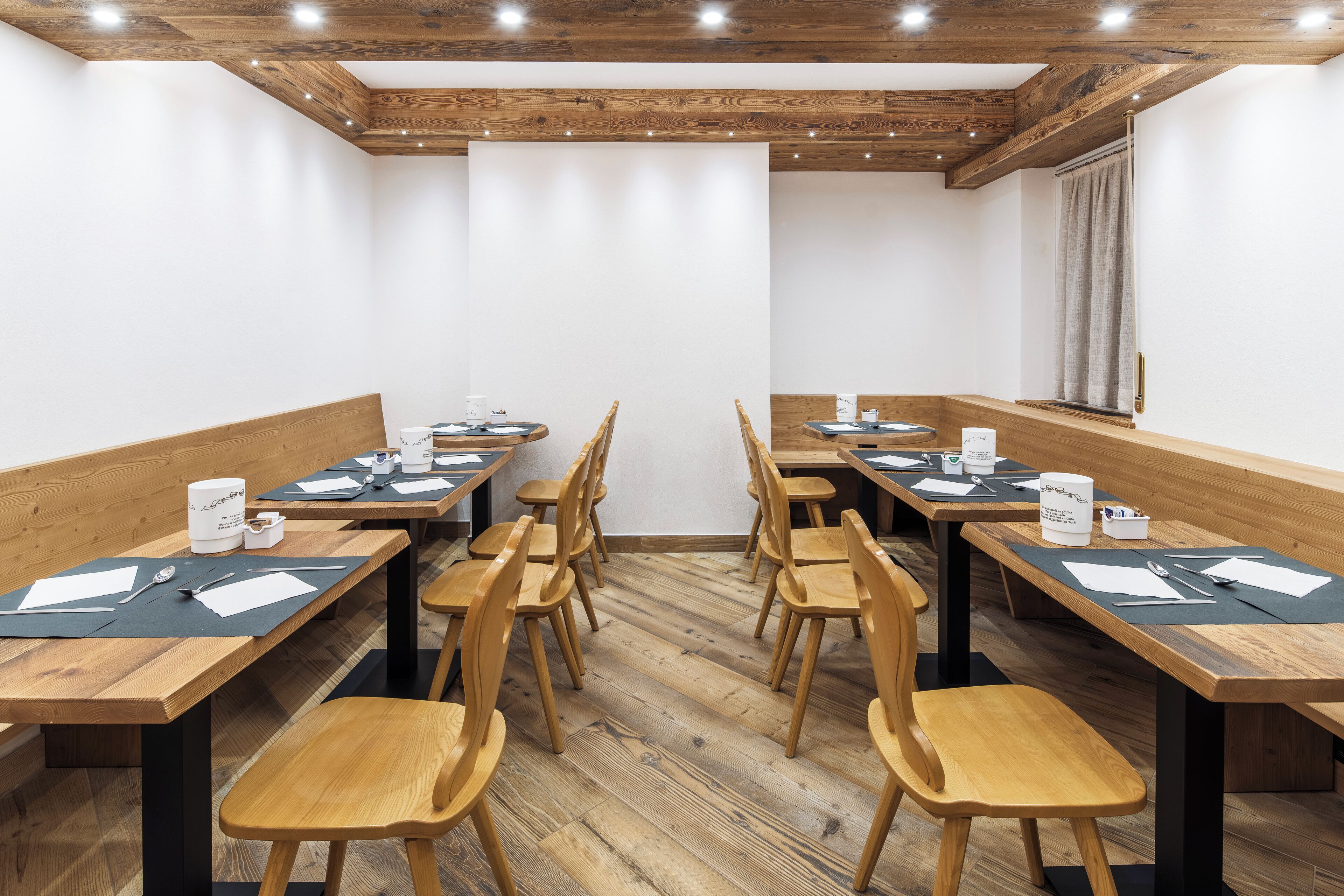 A conference room with wooden tables and chairs, equipped with nameplates, pens, and notepads.