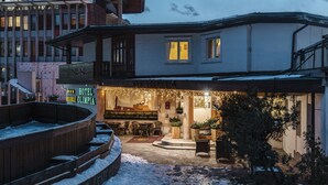 Ein Hotel mit überdachter Außenbestuhlung, einem Pool und schneebedecktem Gelände.