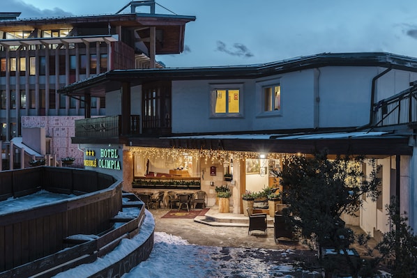Un hotel con un espacio de estar techado al aire libre, una piscina y suelo cubierto de nieve.