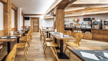 Un restaurante con mesas y sillas de madera, una zona de cocina y un televisor en la pared.